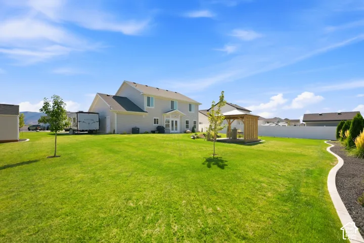 Expansive backyard with a manicured lawn, a detached gazebo structure, and a perimeter privacy fence