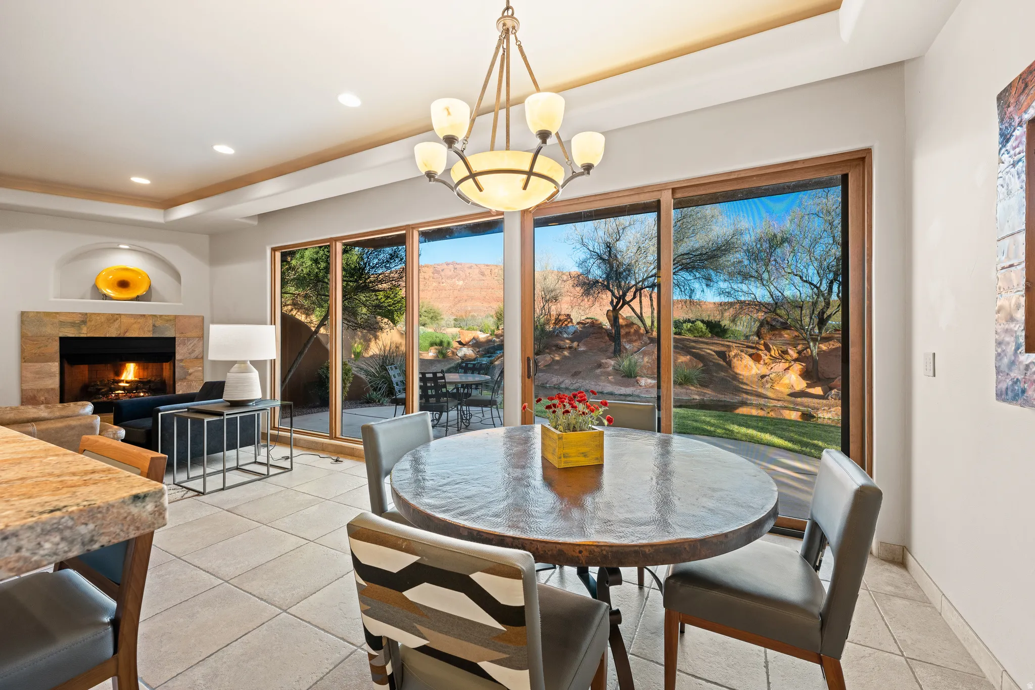 Recessed lighting, tray ceiling, tile flooring, stone fireplace, and sliding glass doors