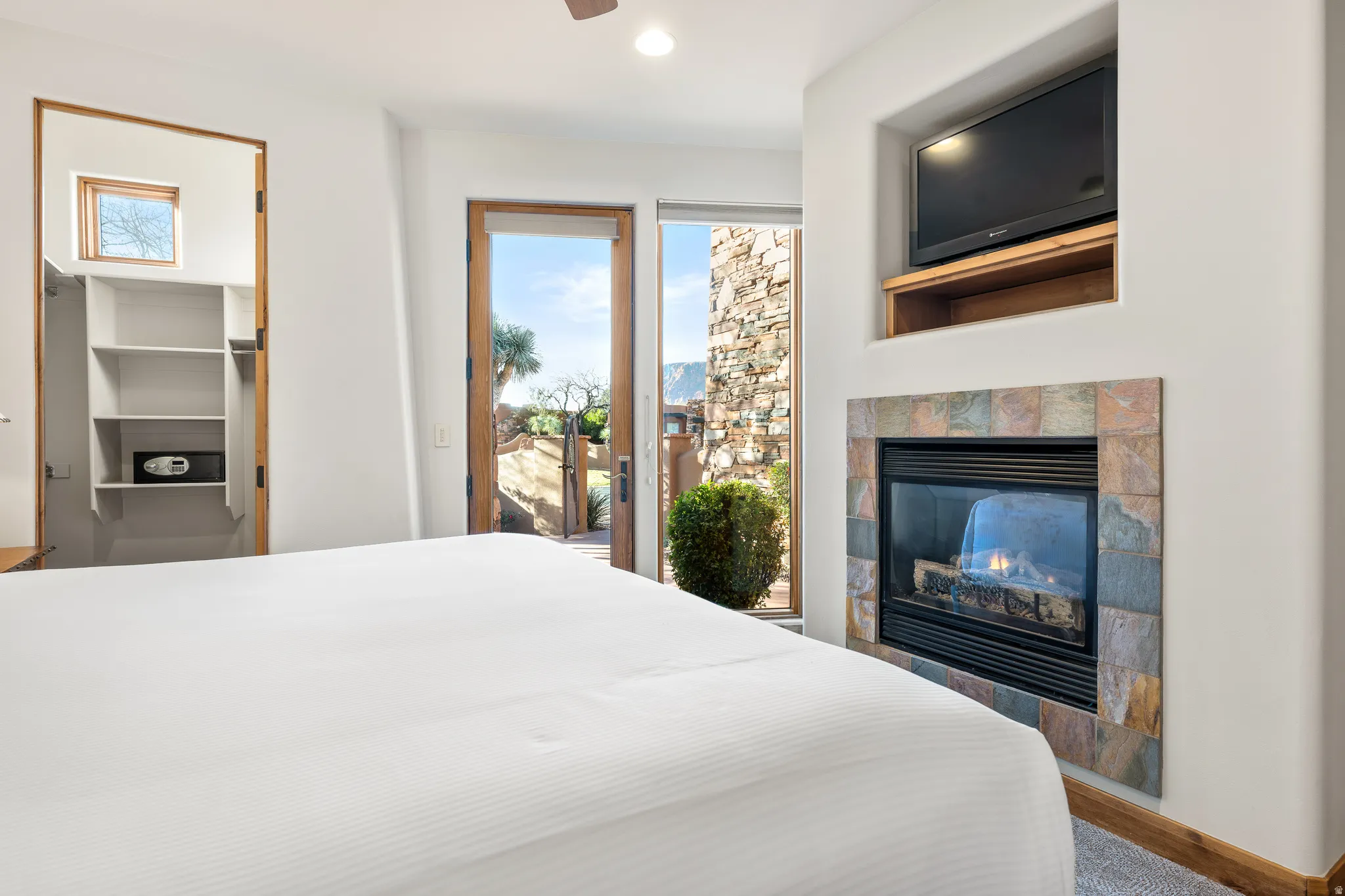 Built-in shelving, glass-paneled door, stone-tiled fireplace, integrated television niche, and wood-finish trim