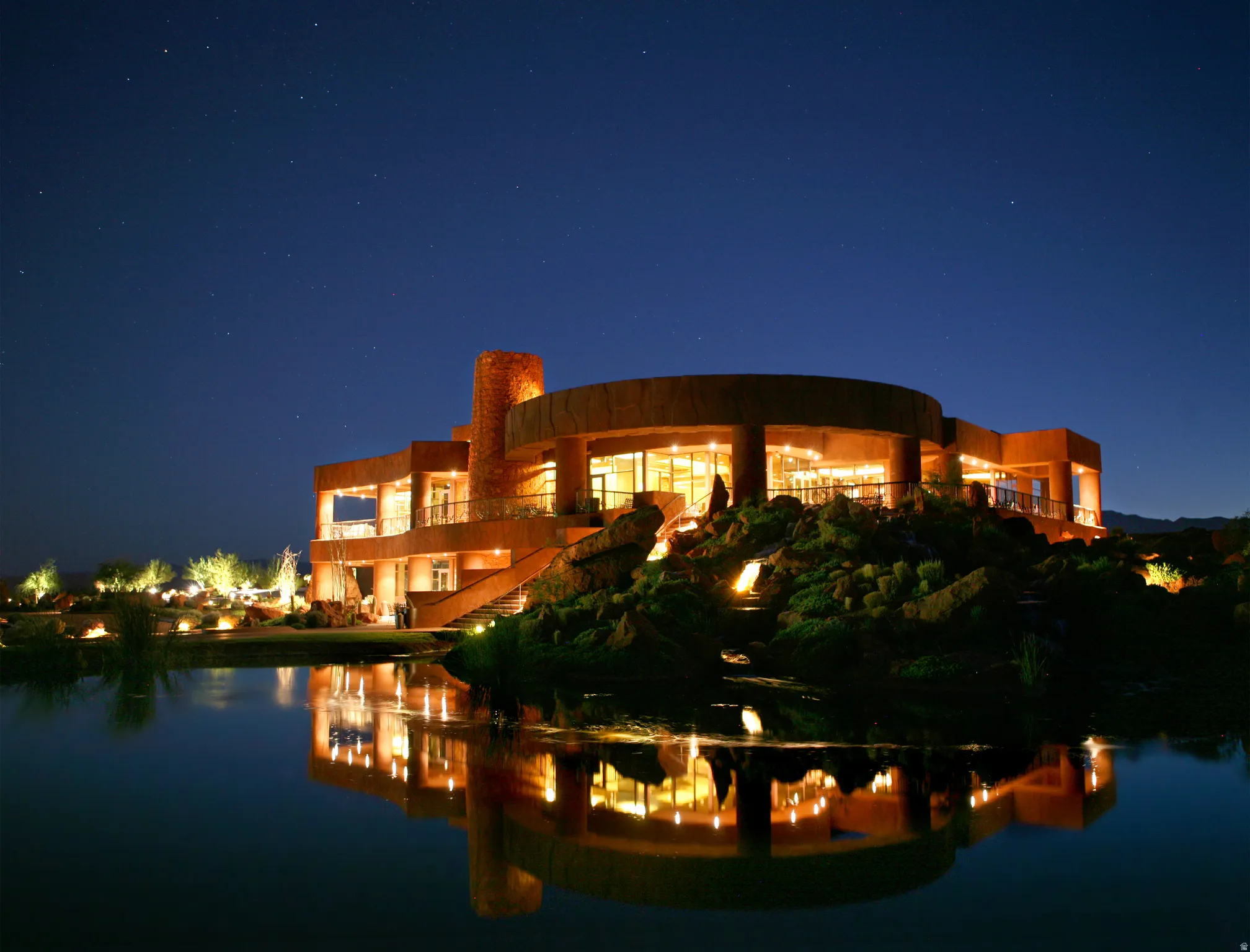 Architectural residence featuring a curved exterior, extensive fenestration, multiple balconies, and integrated exterior lighting