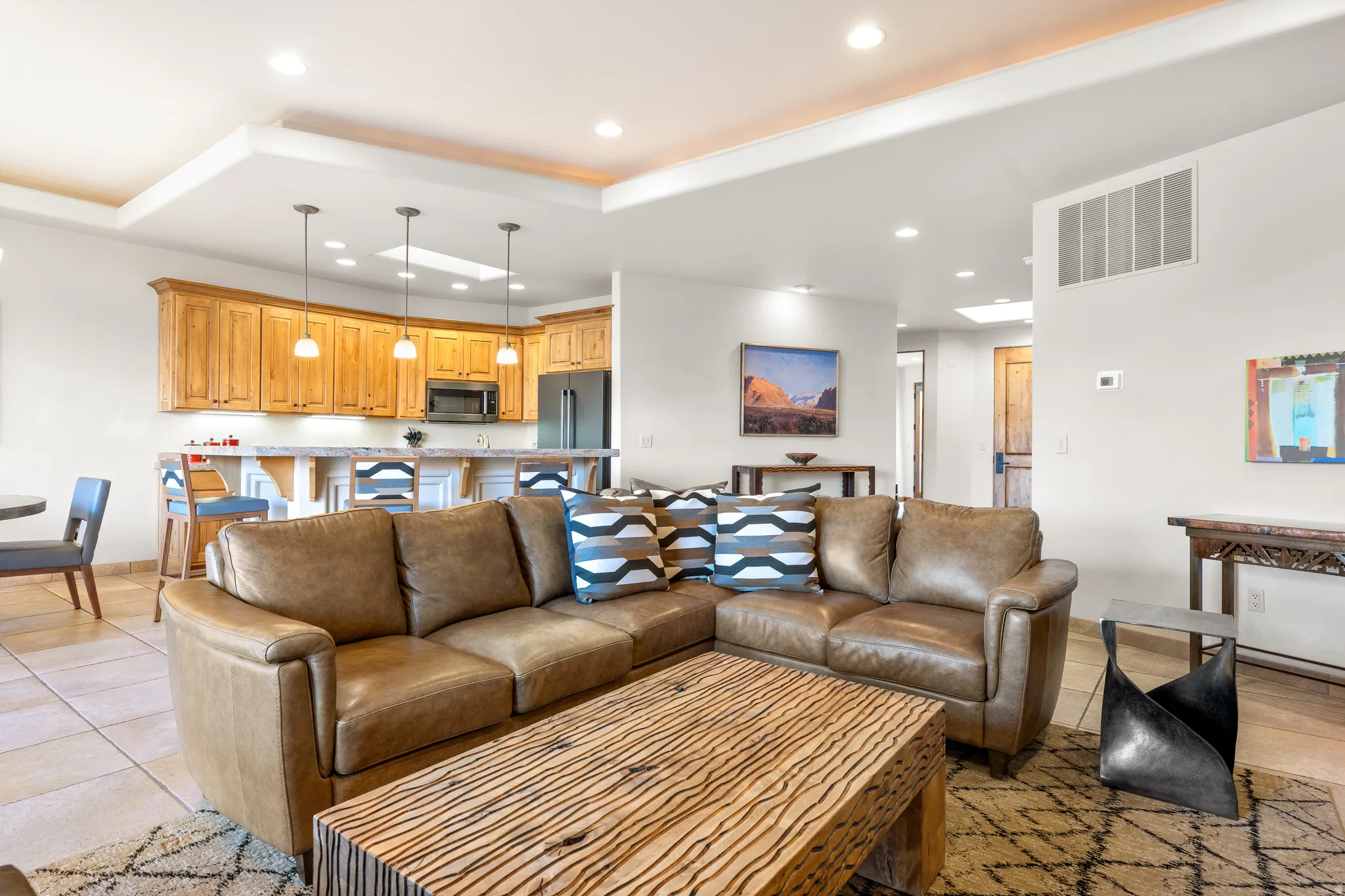 Open-concept living area featuring a kitchen with wood cabinetry and stainless steel appliances