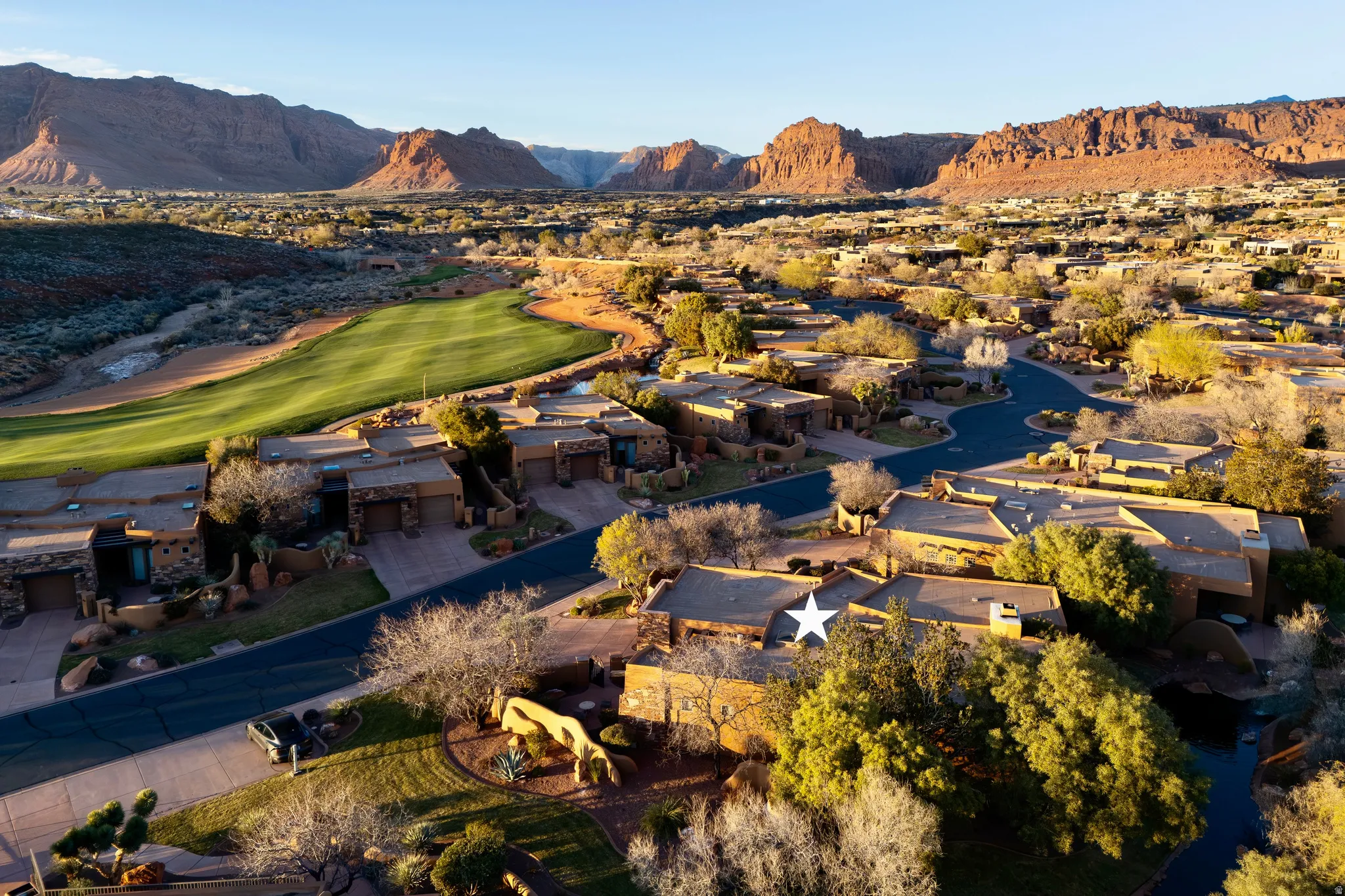 Terraced desert landscaping, paved roadways, and a golf course green, surrounded by mountainous terrain