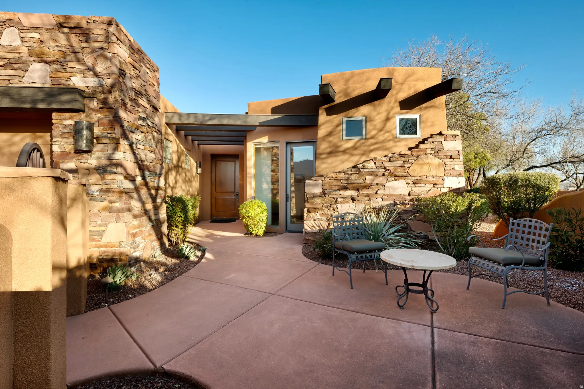 Stucco exterior with stone accents, a covered entry, and a concrete pathway