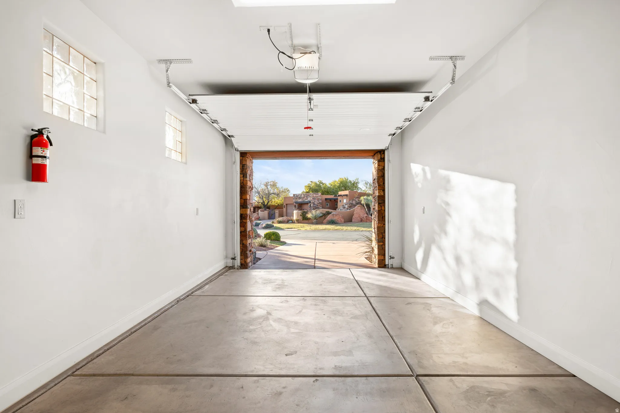 Attached garage featuring concrete flooring, white painted walls, and glass block windows