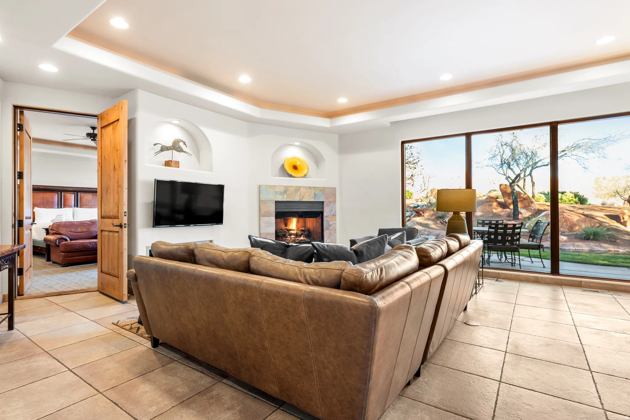 Recessed lighting, tiled flooring, built-in fireplace with stone surround, full-height windows, and a built-in television mount