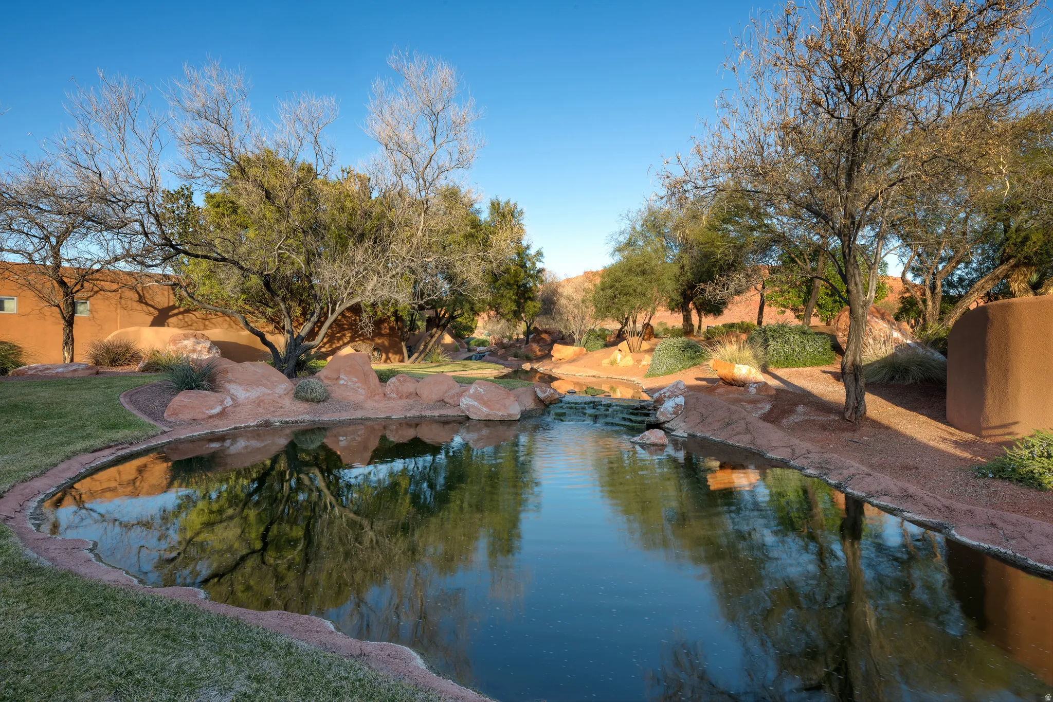 Tranquil pond with natural rock accents, surrounded by mature trees and lush landscaping