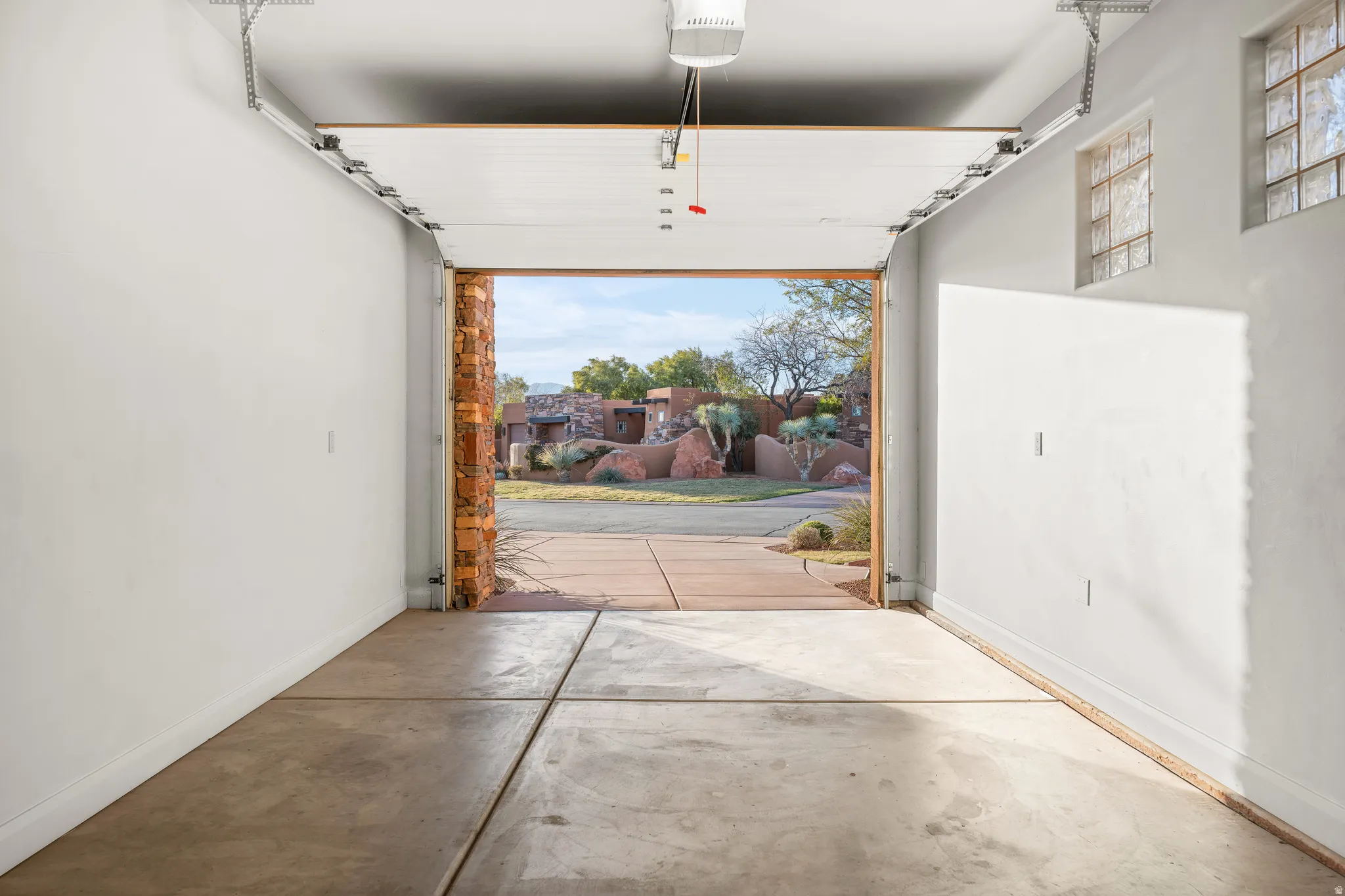 Attached garage with concrete flooring, automatic garage door opener, and two glass block windows