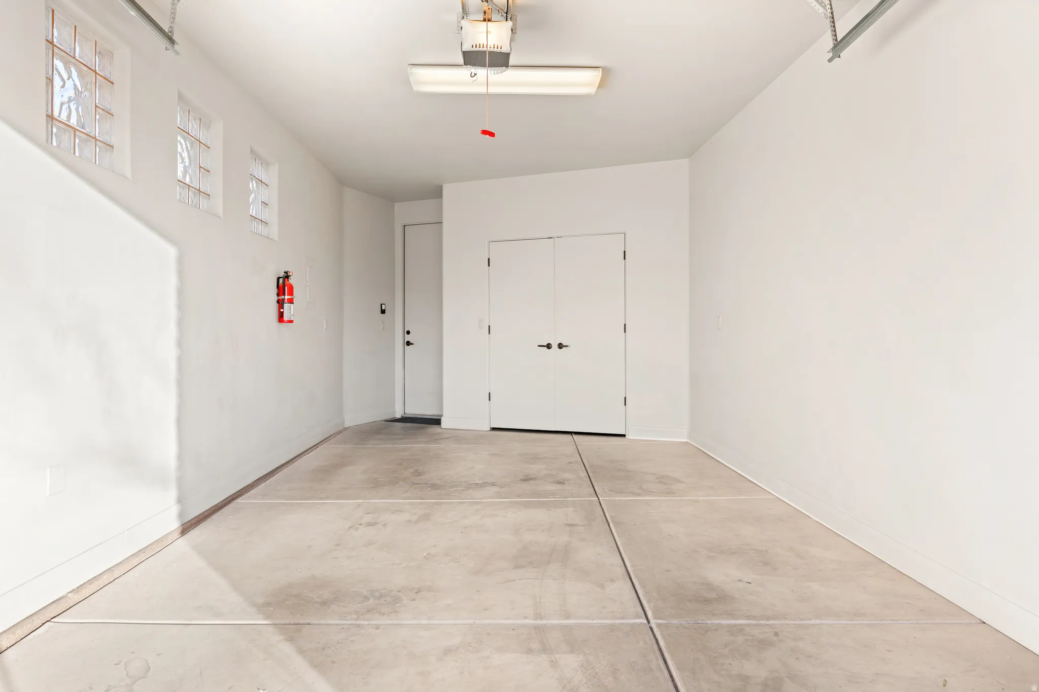 Concrete flooring, overhead lighting, opaque glass block windows, and double doors
