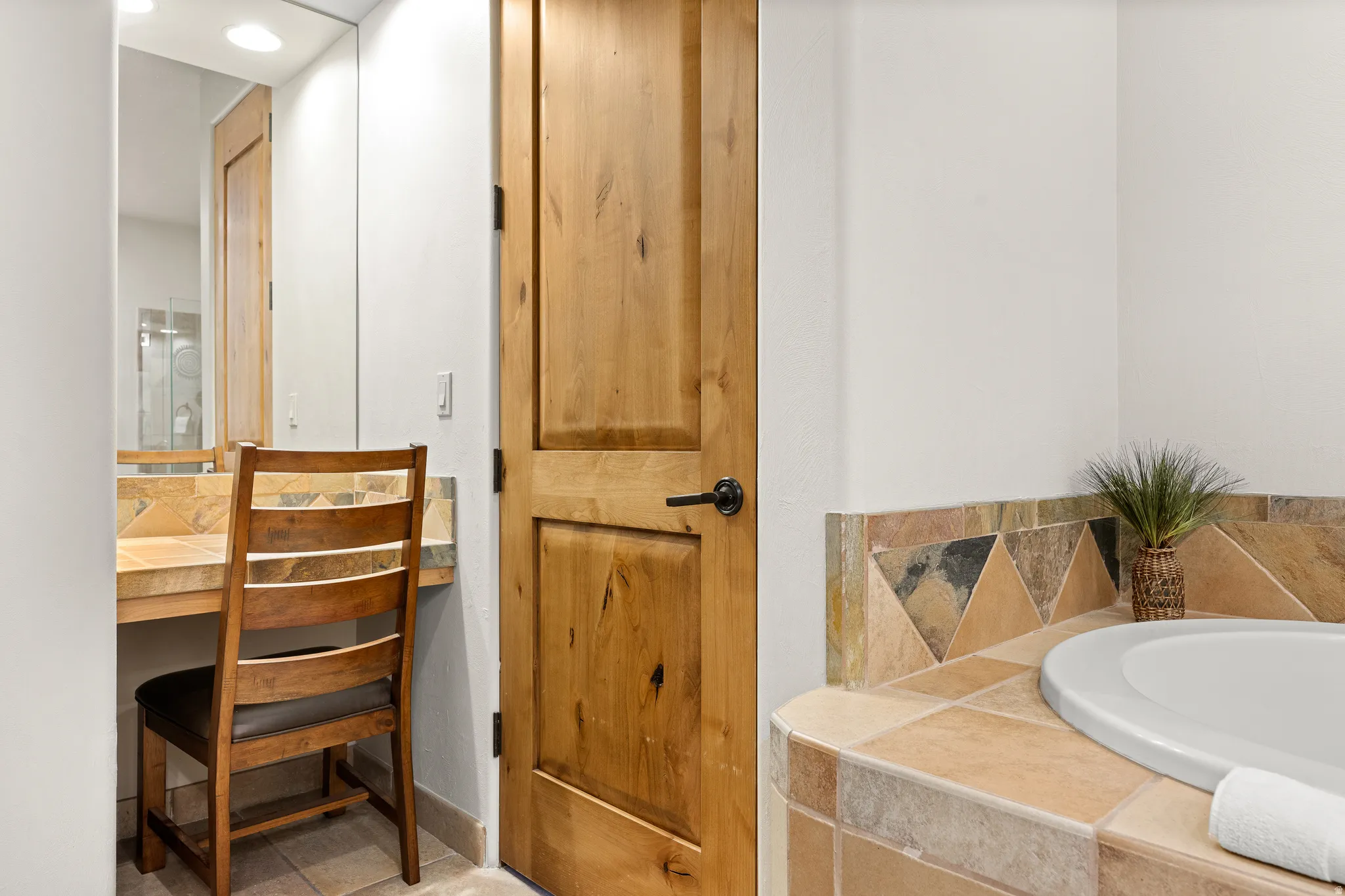 Built-in vanity with stone-tiled countertop and mirror