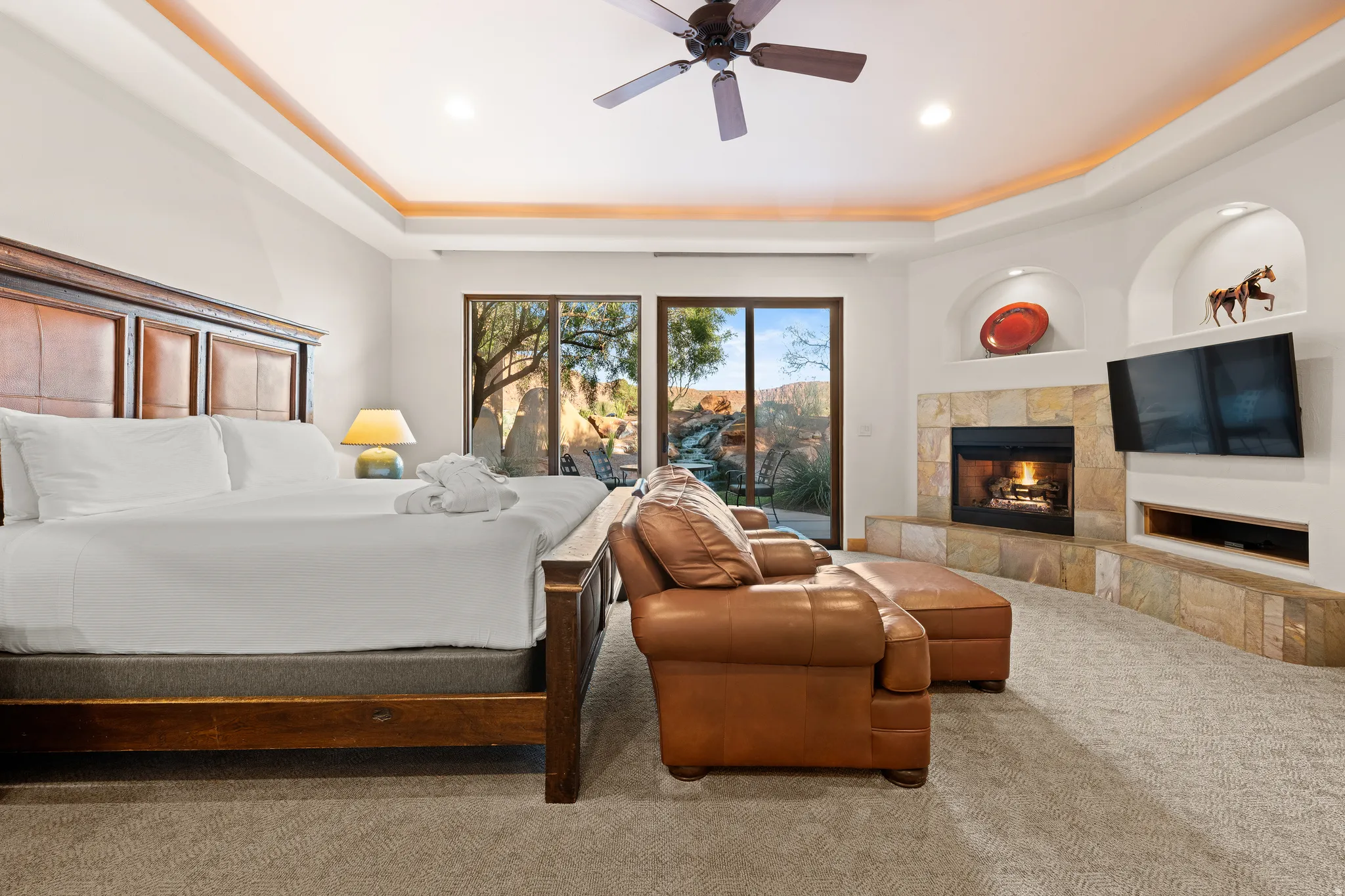 Recessed lighting with a ceiling fan, a built-in fireplace featuring a stone surround, and multiple sliding glass doors