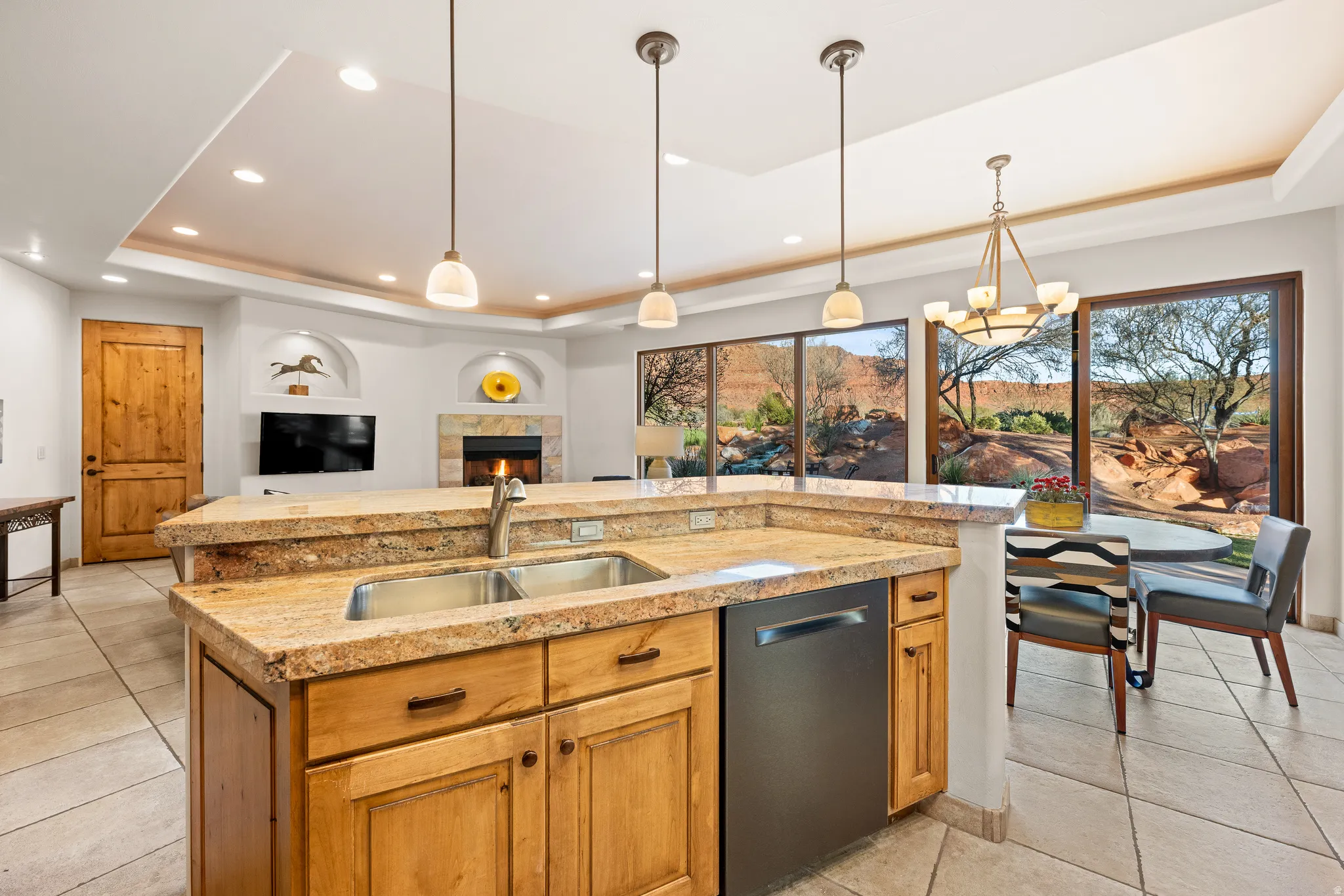 Granite-topped kitchen island with dual sinks, stainless steel dishwasher, and natural wood cabinetry