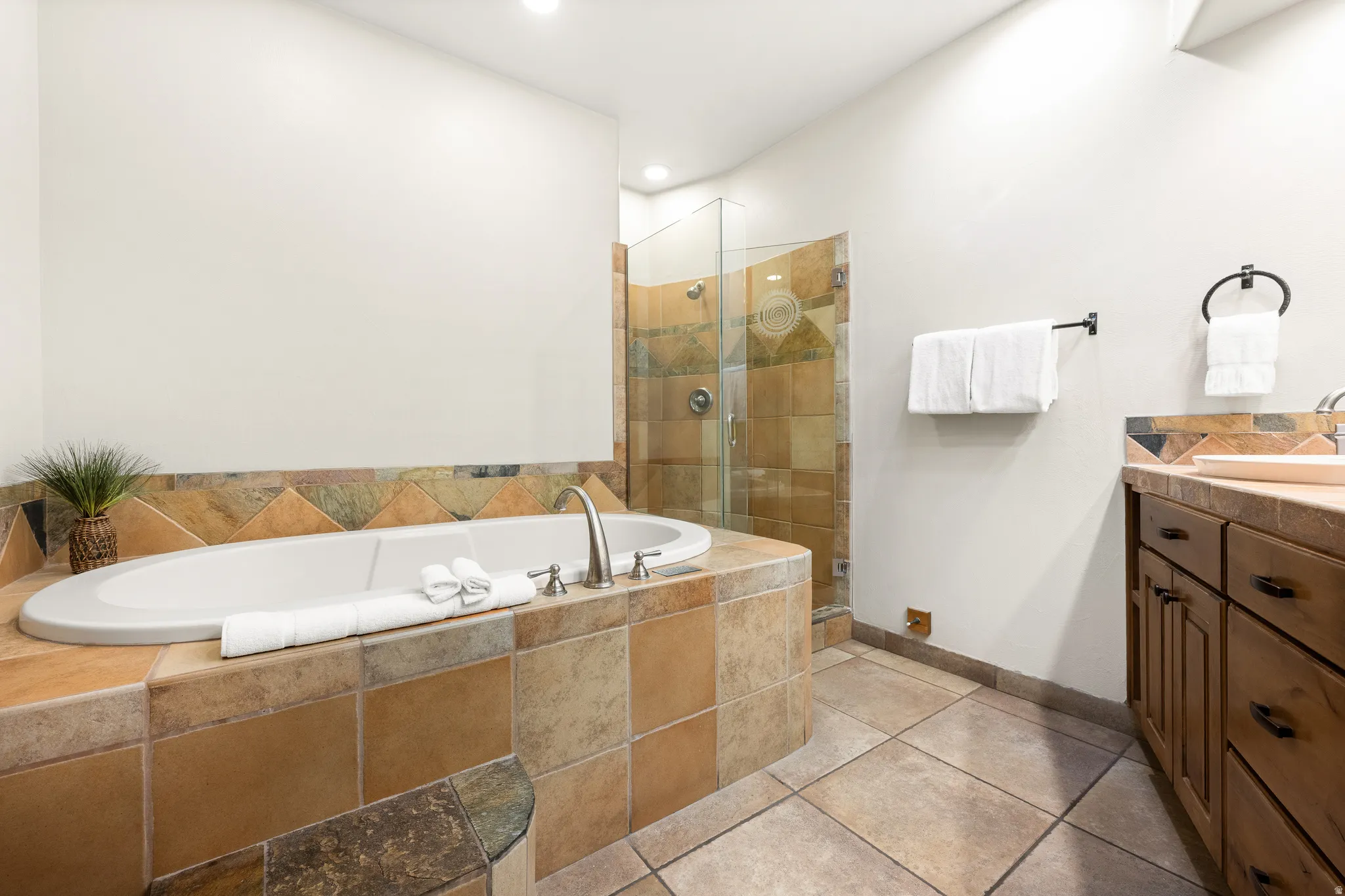 Built-in soaking tub with tile surround, glass-enclosed shower with tile, double vanity with integrated sinks, and wood-finish cabinetry