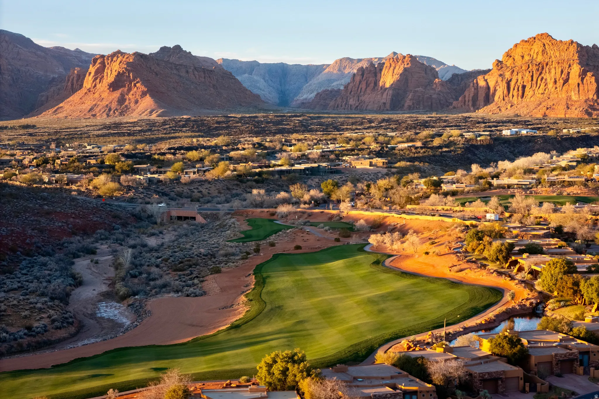 Expansive golf course frontage with surrounding residential properties, distinct red rock mountain backdrop, and scattered desert foliage