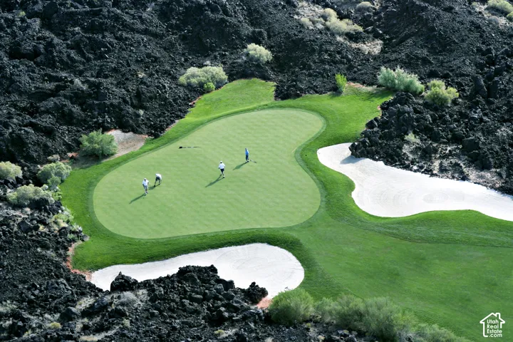Golf course green surrounded by dark rock formations and sand traps