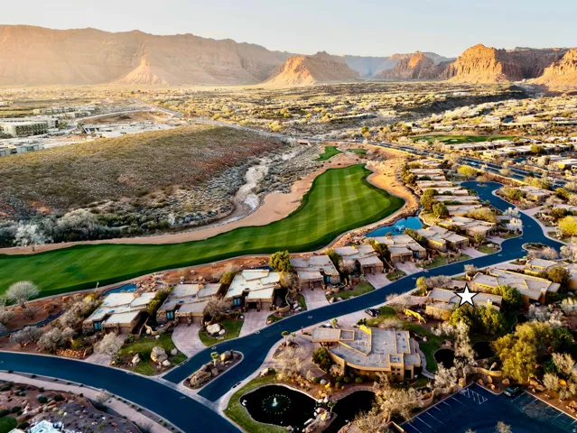 Expansive residential community with rugged mountain backdrop, desert landscaping, and a golf course