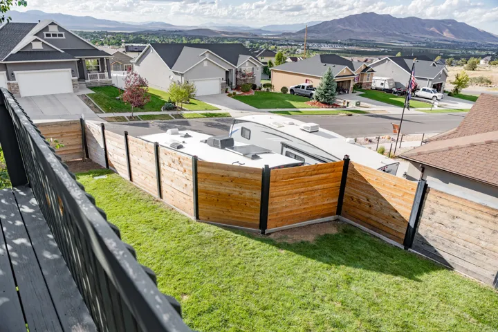 Expansive backyard featuring a manicured lawn, wood-paneled privacy fence, and mountain backdrop