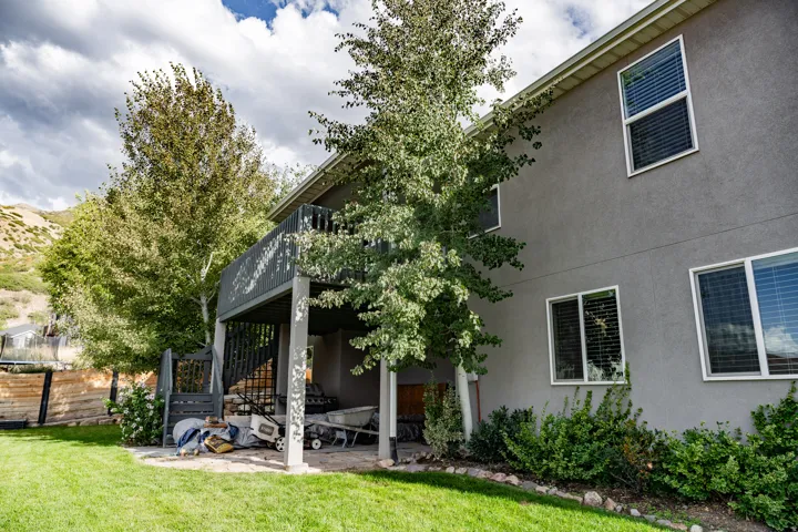 Stucco exterior with multiple windows, an elevated deck, and a ground-level patio