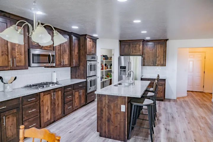 Kitchen featuring dark wood cabinetry, light-toned countertops, stainless steel appliances, and wood-finish flooring