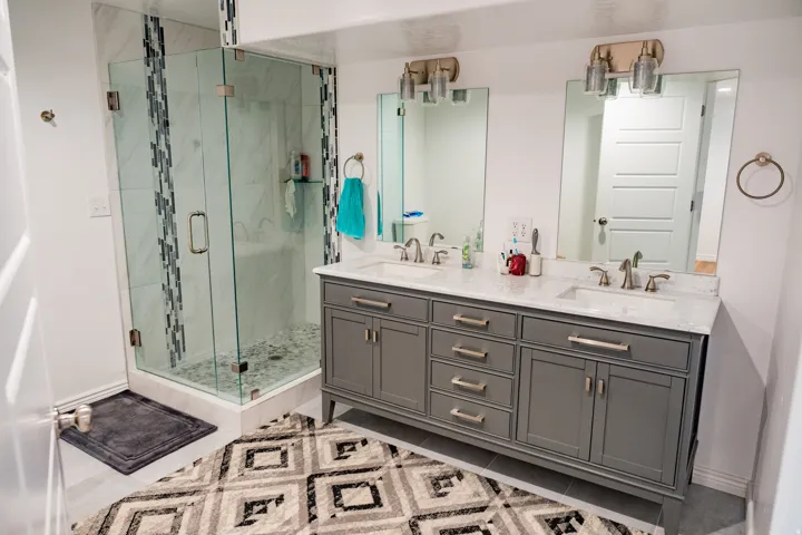 Dual vanity with gray cabinetry and stone-look countertops