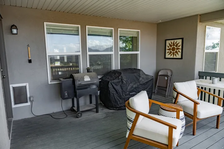Covered outdoor deck with a textured ceiling, multiple windows, and a wall-mounted light fixture