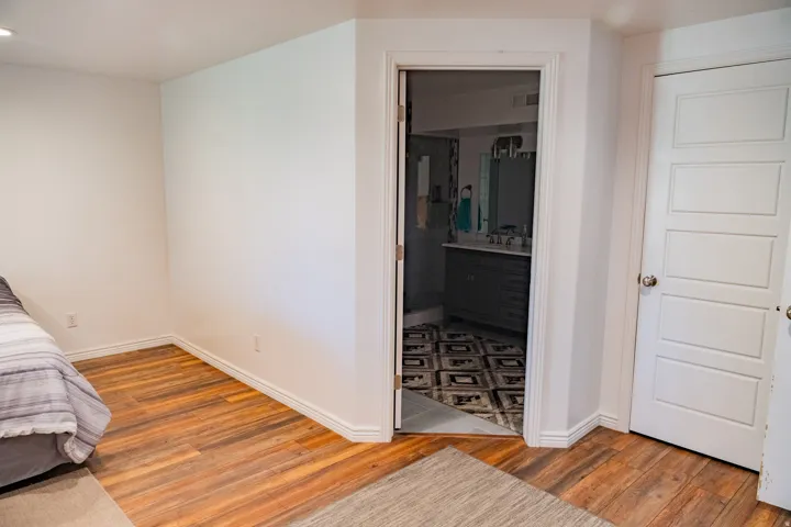 Wood-finish flooring, white walls, and a white interior door with paneling