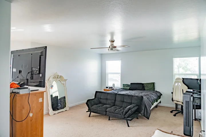 Carpeted flooring, ceiling fan, and multiple windows with blinds