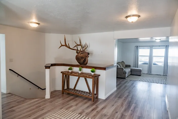 Wood-finish flooring, staircase with dark handrail, interior archway, and recessed lighting