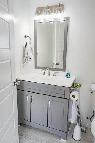 Light gray vanity with brushed nickel hardware, white countertop, rectangular undermount sink, brushed nickel faucet, and framed mirror