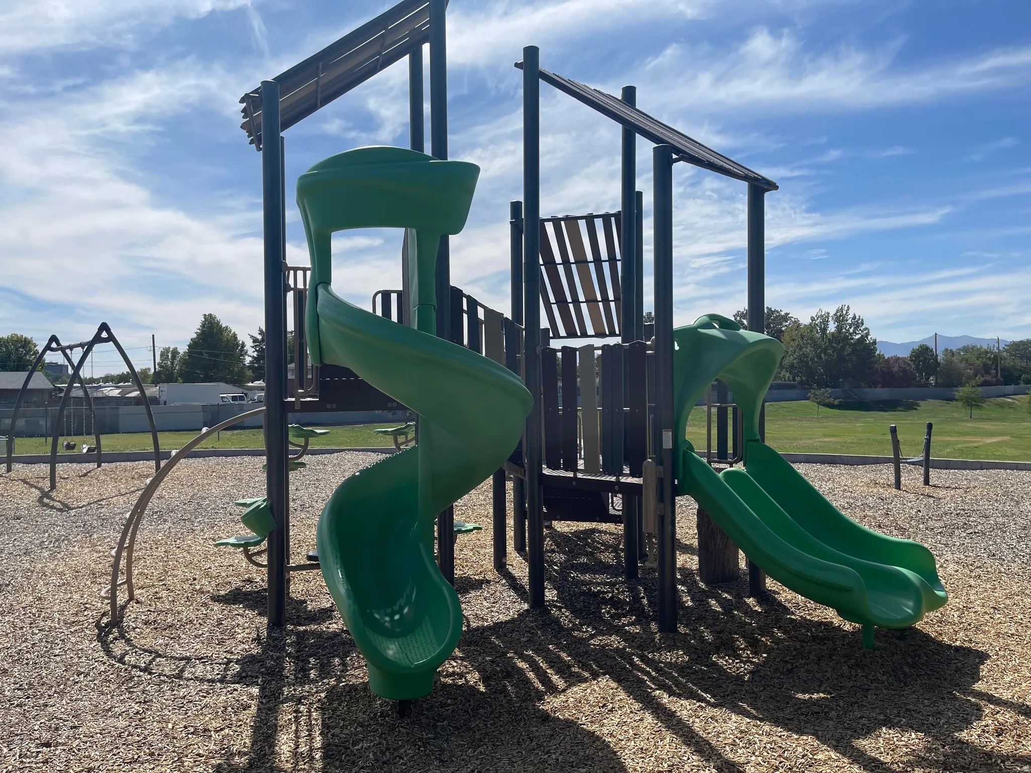 Neighboring Scott Avenue Park - Recreational playground featuring two green slides, climbing elements, and a swing set on a wood chip surface