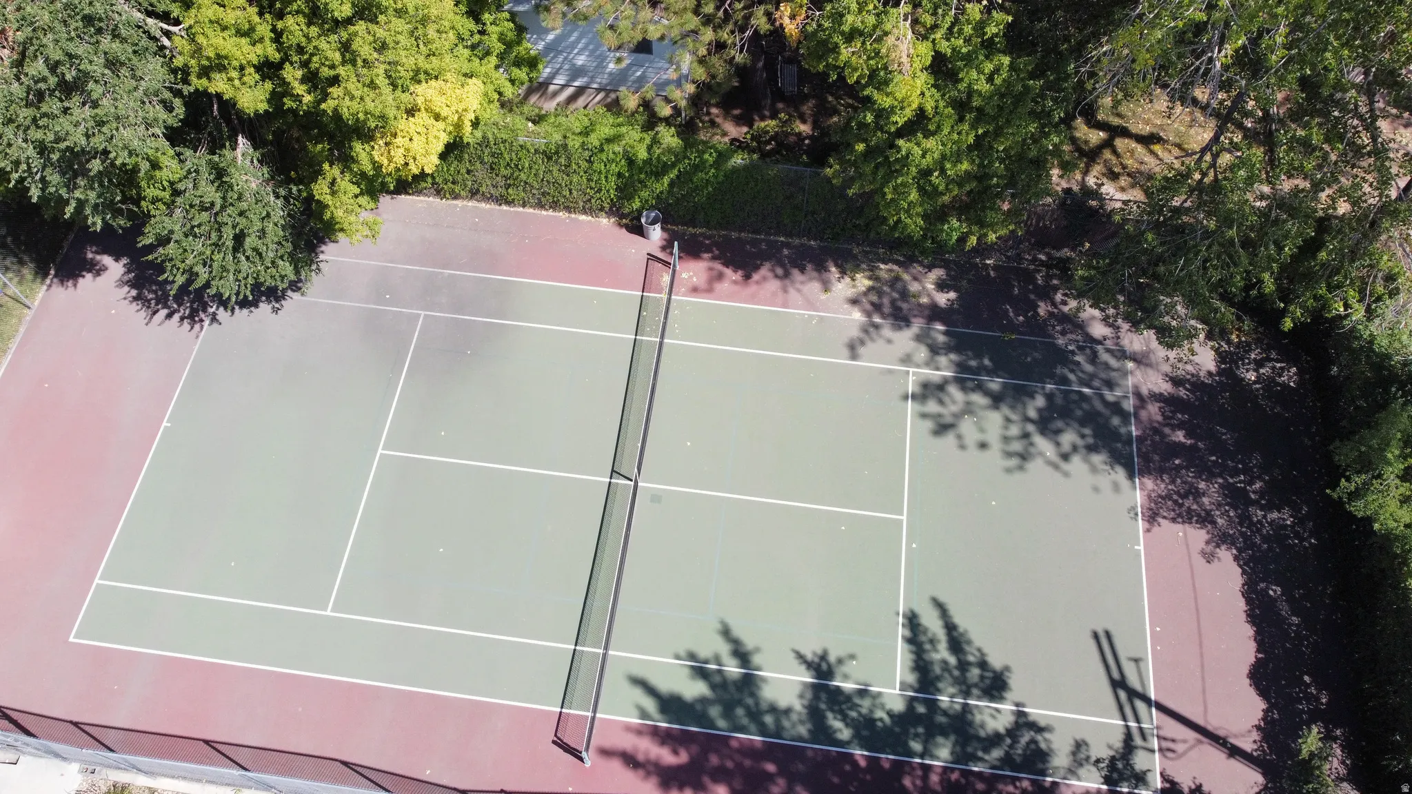 Full-size tennis court with a green playing surface and red perimeter
