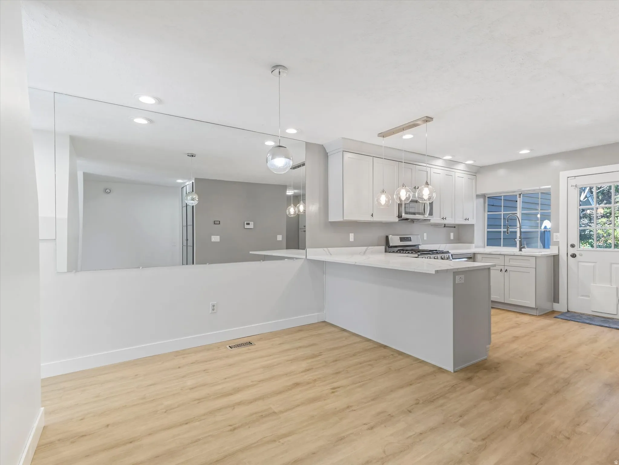 Kitchen featuring white cabinetry, stainless steel appliances, a white countertop, and wood-finish flooring
