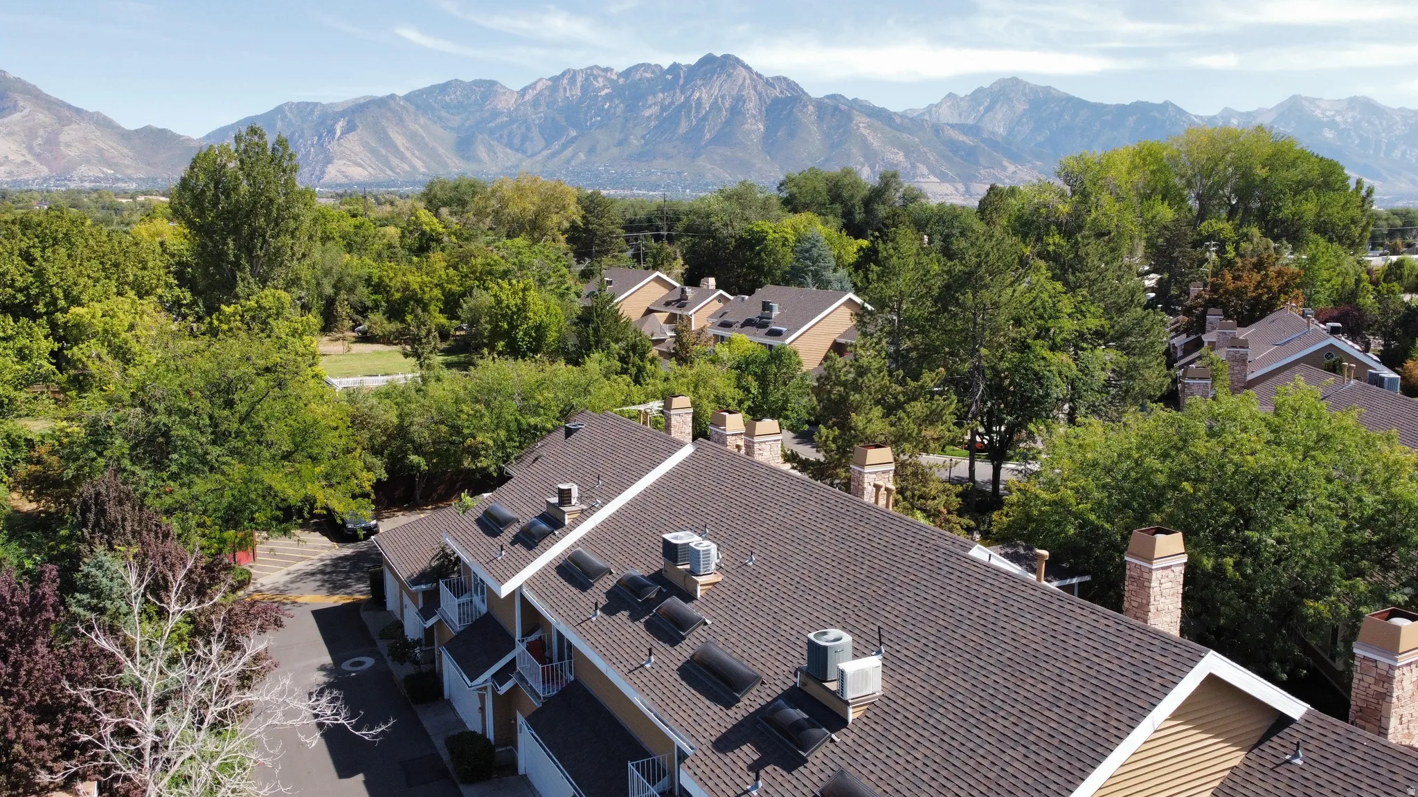 Townhome community featuring pitched composition shingle roofs, dormer windows, and brick chimneys