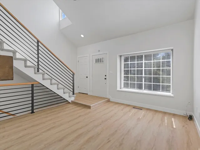 High ceilings with skylight, modern metal and wood railing, wood-finish flooring, recessed lighting, and a large multi-pane window