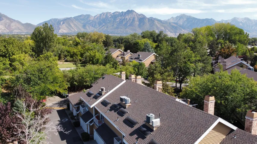 Townhome community featuring pitched composition shingle roofs, dormer windows, and brick chimneys