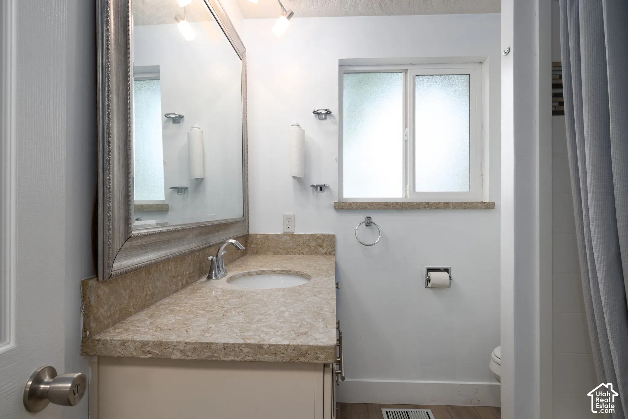 Vanity with an integrated sink, polished chrome faucet, and stone countertop