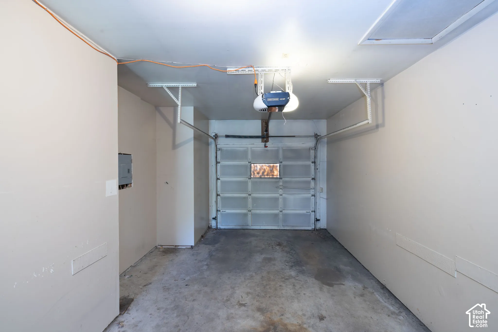 Garage with a concrete floor, an overhead garage door opener, and a panel-style garage door with window inserts