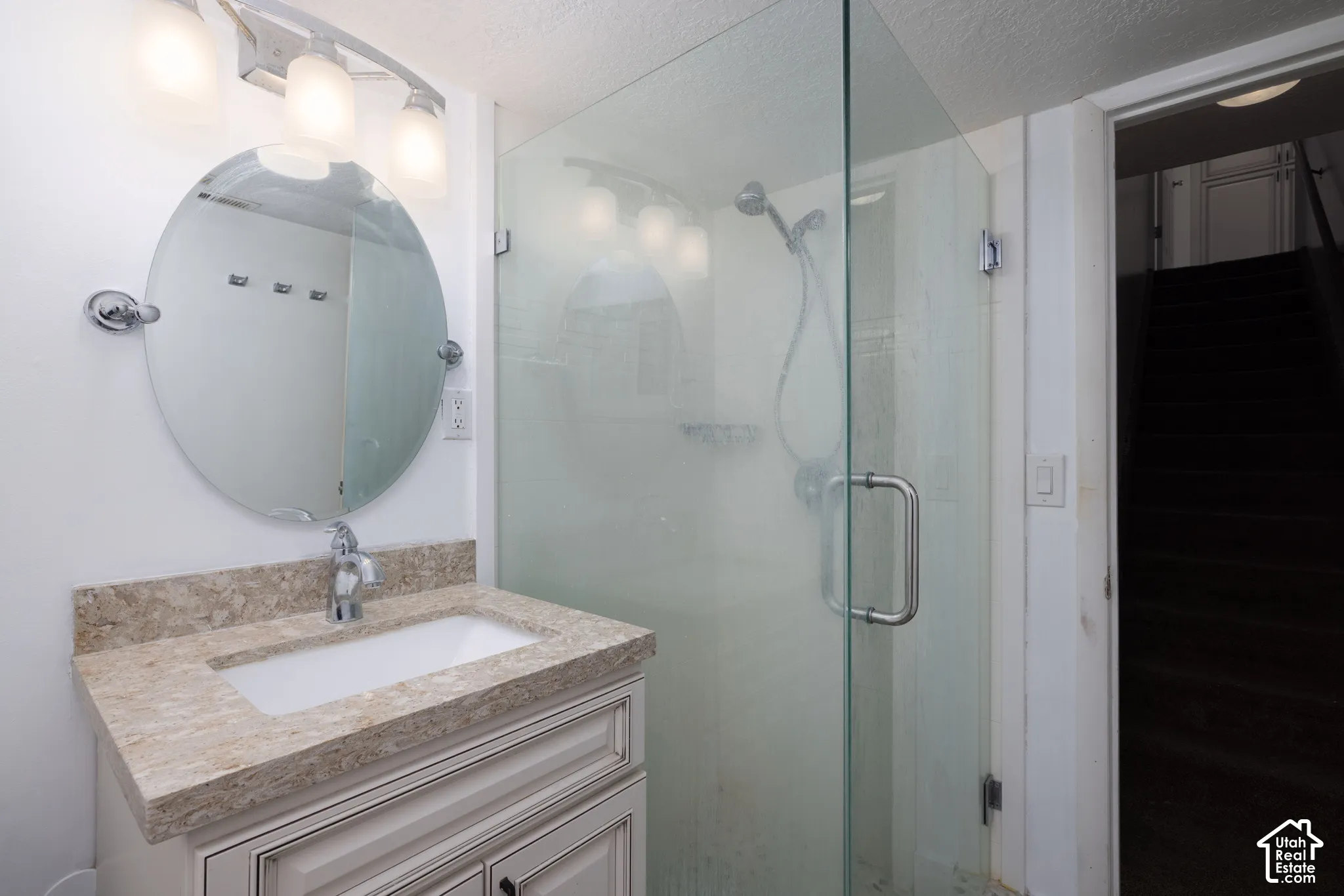 Vanity with a stone-finish countertop, undermount sink, and chrome faucet