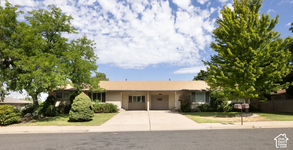 Ranch-style exterior with a low-pitch roof, two integrated garages, a concrete driveway, and mature landscaping