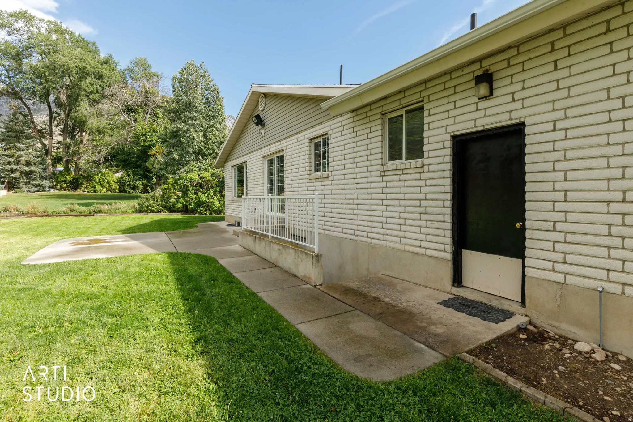 Brick exterior with white mortar, concrete patio, and a grassy yard