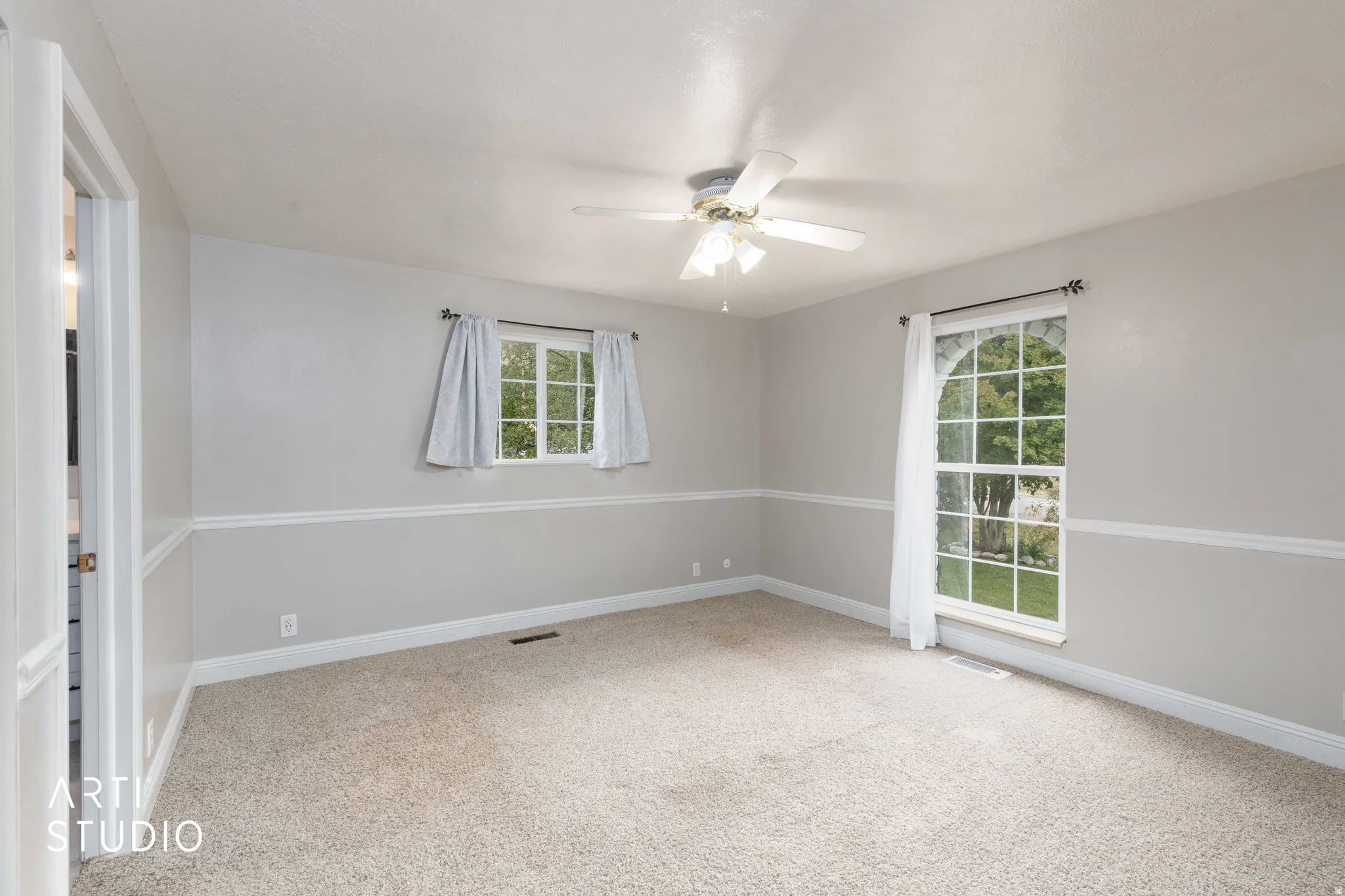 Carpeted bedroom with a ceiling fan, a double-hung window, and an arched window
