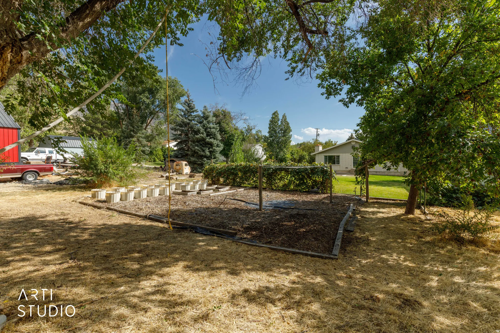 Expansive outdoor space featuring mature trees, a designated garden area, and a red-sided outbuilding