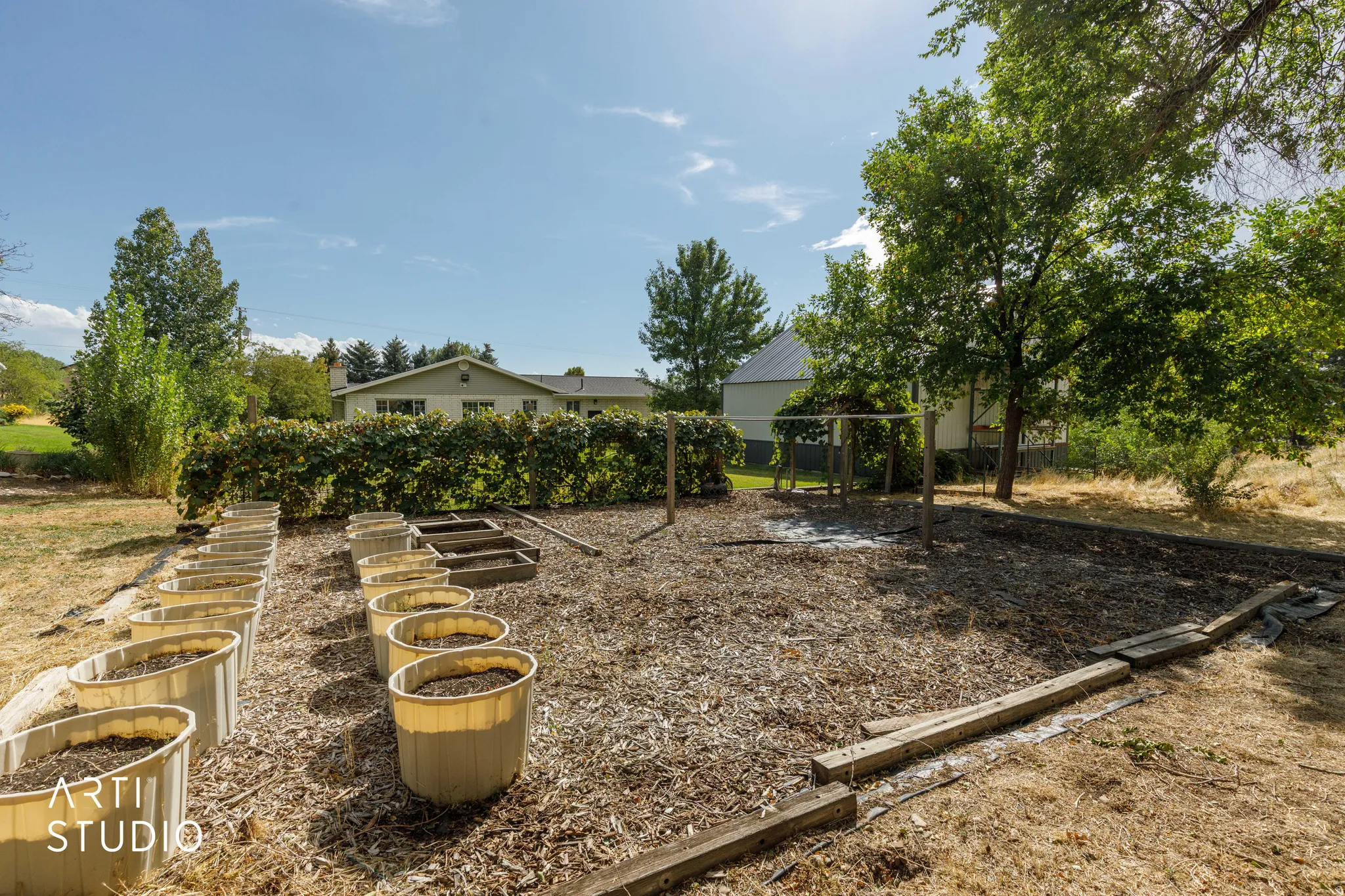 Expansive outdoor space featuring a garden area with raised beds, mature trees, and a privacy hedge