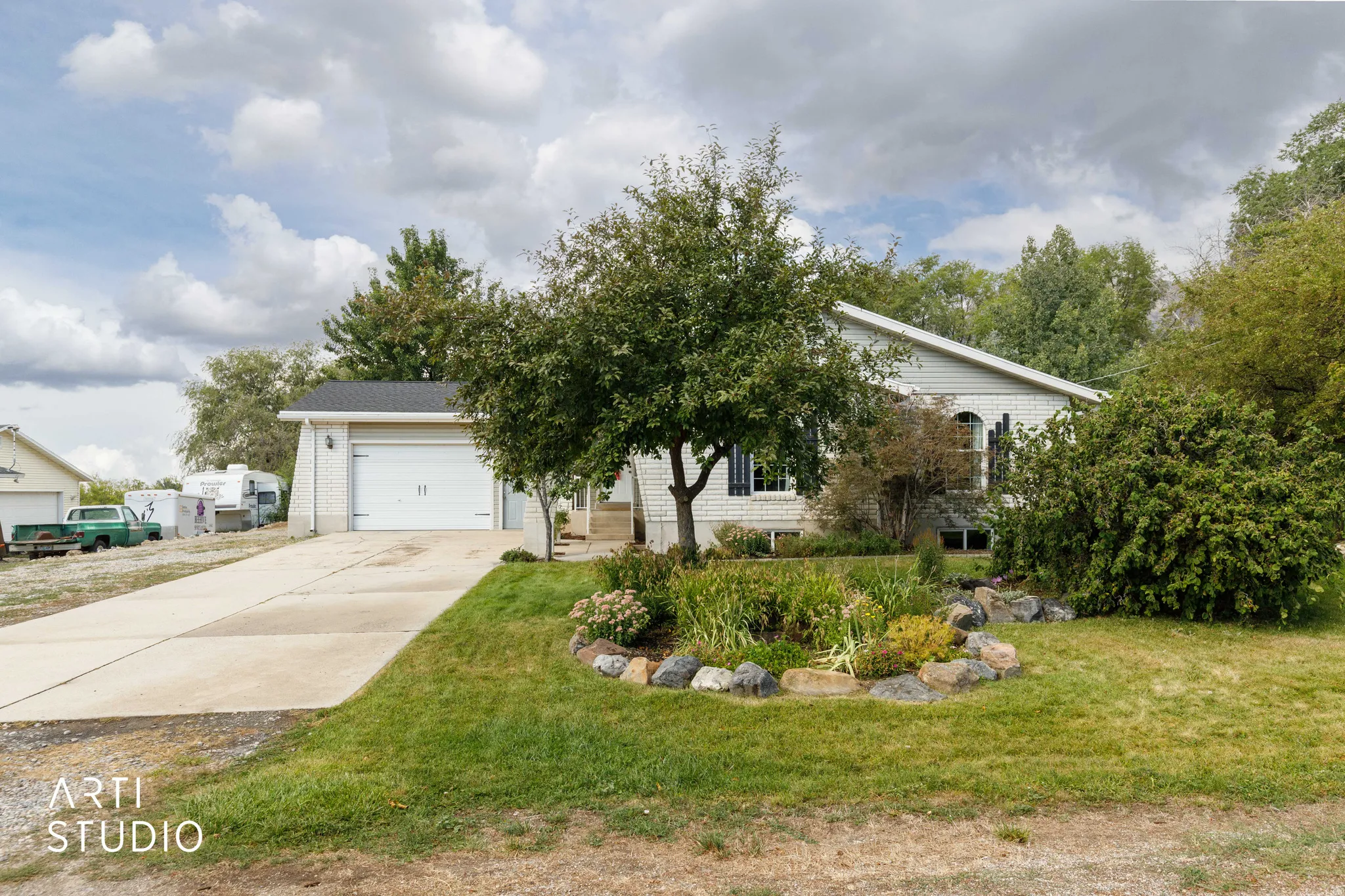 Siding exterior with a two-car garage, concrete driveway, and established landscaping