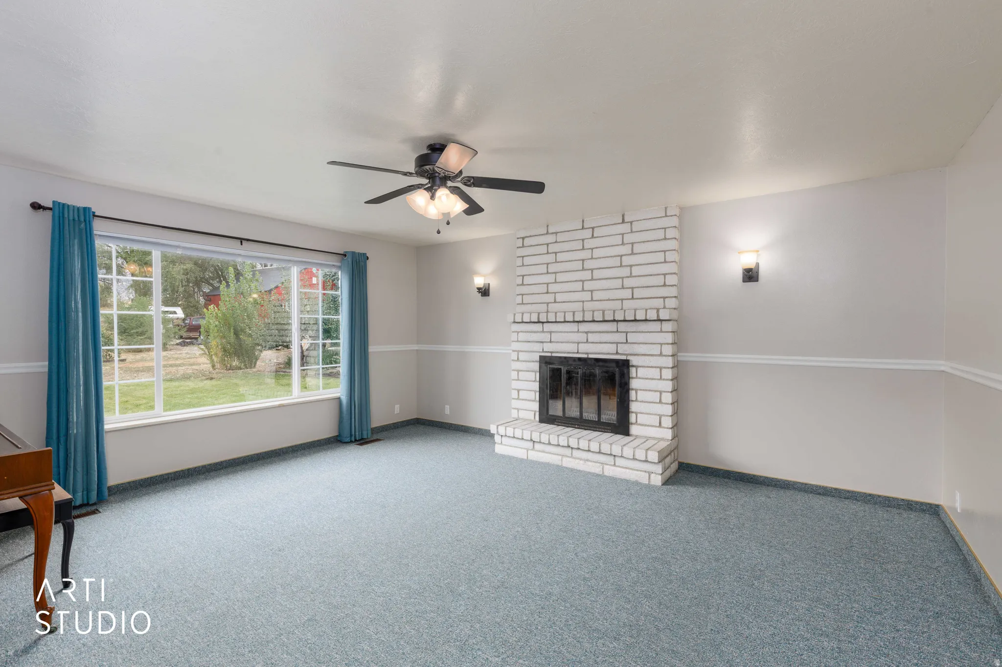 White brick fireplace with an integrated firebox, ceiling fan with light fixture, large picture window, and wall sconces