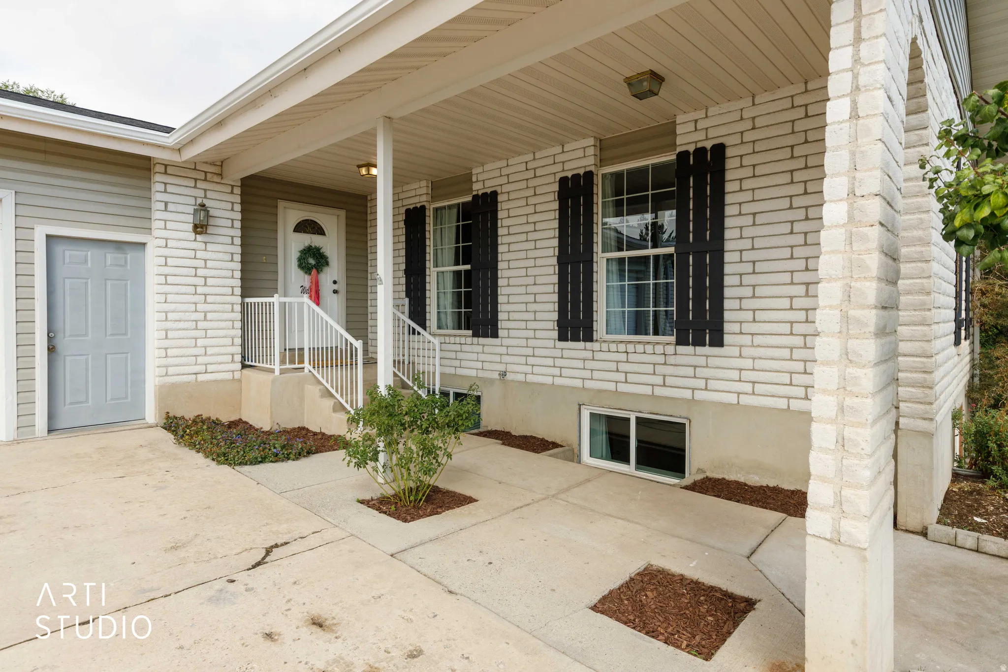 Brick exterior with horizontal siding accents, covered front porch, white railings, and concrete pathway