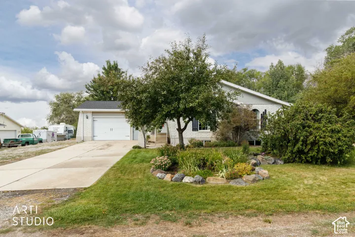 Siding exterior with a two-car garage, concrete driveway, and established landscaping