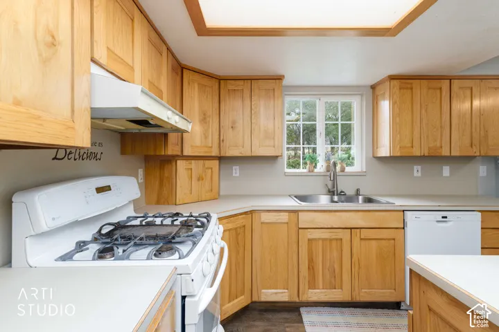 Wood cabinetry, solid surface countertops, stainless steel sink, built-in gas range, and a window with a garden grid