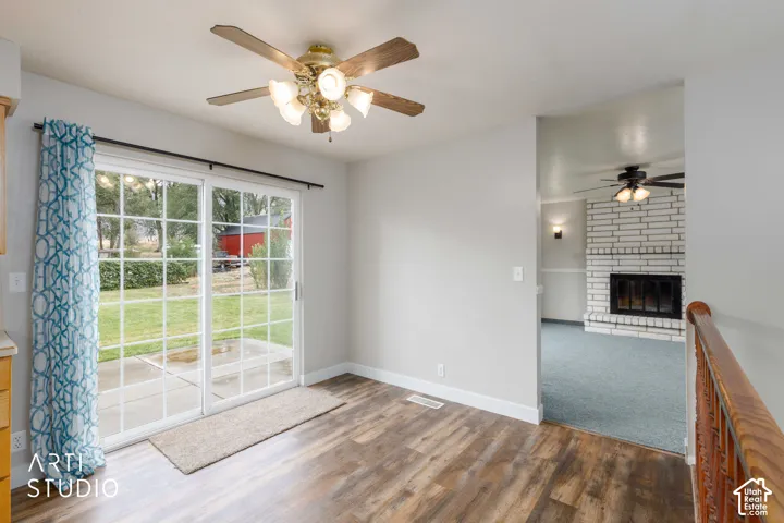 Sliding glass patio door with grid panes, wood-finish flooring, and a ceiling fan with integrated lighting