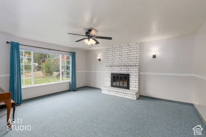 White brick fireplace with an integrated firebox, ceiling fan with light fixture, large picture window, and wall sconces