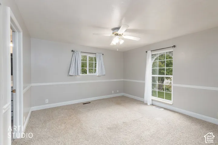 Carpeted bedroom with a ceiling fan, a double-hung window, and an arched window